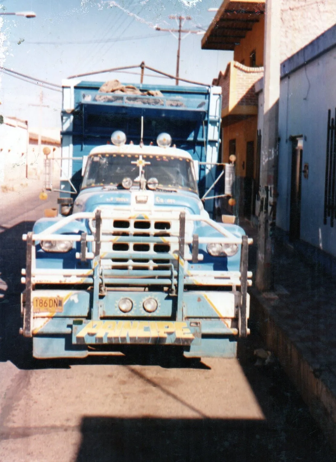 Fotografía antigua del primer camión, azul con defensa cromada, en una calle de Sayula