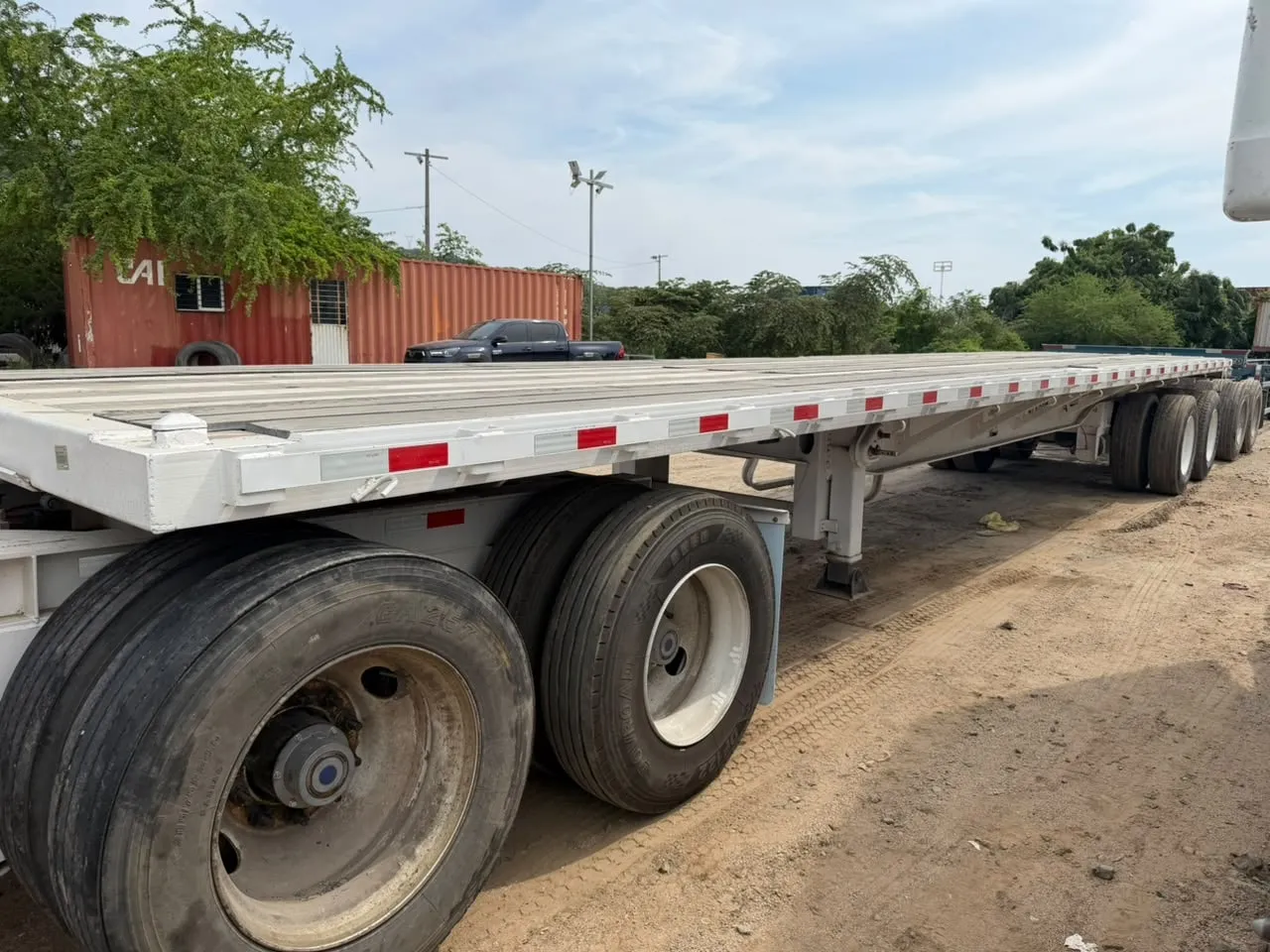 Remolque de plataforma blanco de TRANSEVAN estacionado en el patio